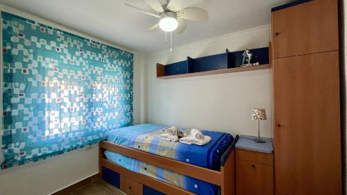 ein kleines Schlafzimmer mit einem blauen Bett und einem Deckenventilator in der Unterkunft Playa mar by Gloove in San Juan de los Terreros