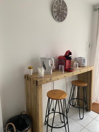 une table en bois avec deux tabourets et une horloge sur le mur dans l'établissement Chez fifi&stella, à Neufmoutiers-en-Brie