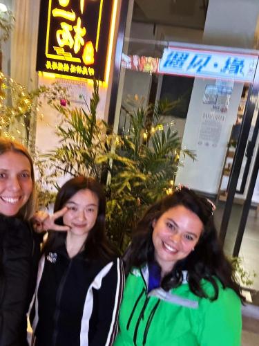 three women posing for a picture in front of a store at Zhangjiajie Twelve Warm Inn-Tianmen Mountain Ropeway Station in Zhangjiajie