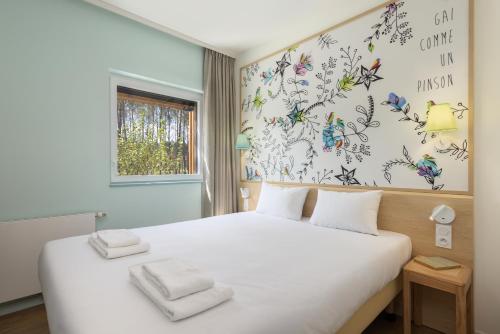 - une chambre avec un lit blanc et un mur orné de papillons dans l'établissement Center Parcs Les Landes de Gascogne, à Beauziac