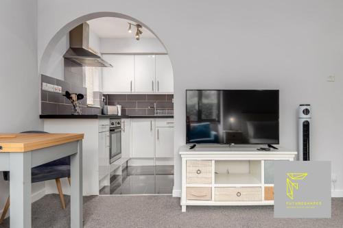 a kitchen with white cabinets and a large tv at GuestReady - Cosy Wimbledon Studio Flat in London