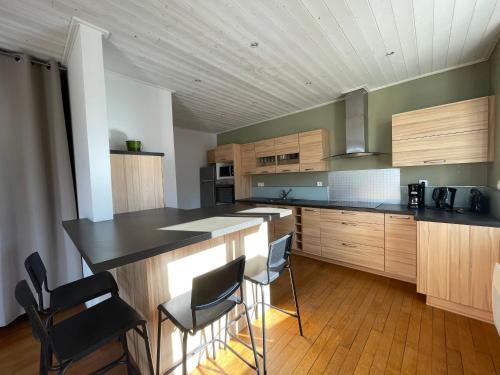 une cuisine avec des placards en bois et un îlot avec des chaises dans l'établissement Le logis des Halles, à Cerizay