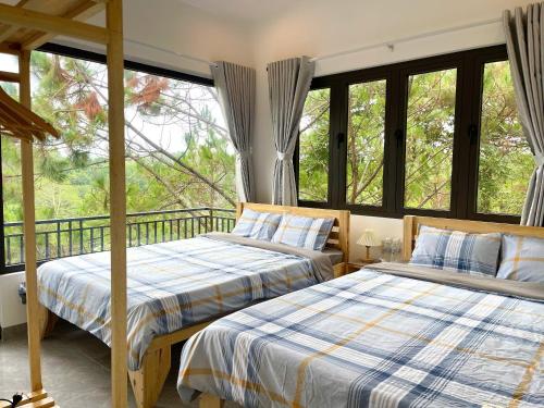 two beds in a room with windows at Angels Homestay & Coffee - Măng Đen in Kon Von Kla