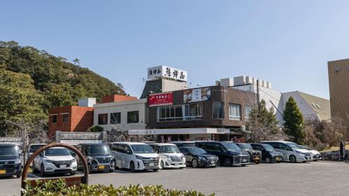 a parking lot with cars parked in front of a building at 琴弾荘 in Kanonji