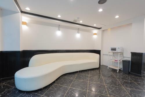 a white couch in a room with a wall at Minutes from Sumiyoshi & Iconic Attractions & Sky Tree in Tokyo