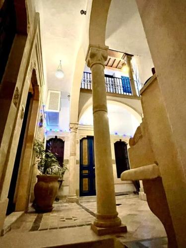 a hallway with a pillar and a potted plant in a building at Dar Andrea in Sousse