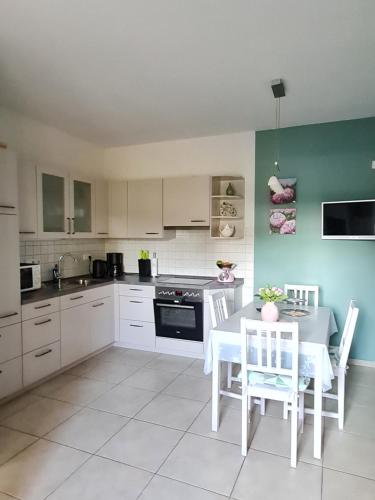 a kitchen with white cabinets and a table and chairs at Ferienwohnung am Hünenweg in Berge