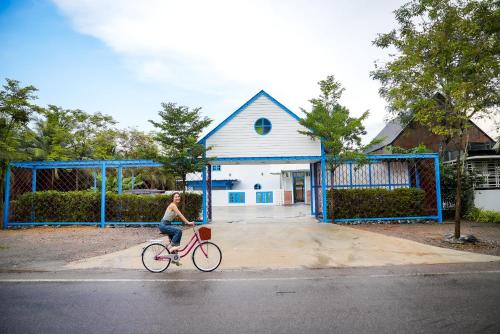 une femme faisant du vélo devant une maison dans l'établissement Standard, à Ban Phrom Min