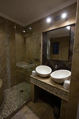 a bathroom with two sinks and a shower at Waterfalls Boutique Hotel in Pretoria