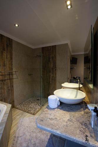 a bathroom with two sinks and a tub and a shower at Waterfalls Boutique Hotel in Pretoria