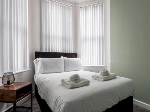 a bedroom with two towels on a bed with windows at 1 Abdiel House · Modern Apartment by Hartlepool Marina Relaxing Pass the Keys in Hartlepool