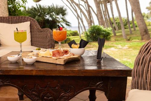a table with a tray of food and two wine glasses at Hotel Cala Caterina in Villasimius