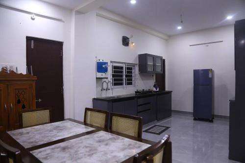 a kitchen with a table and a kitchen with a refrigerator at Veetil-PentHouse, 2BHK, KPHB, Hyderabad in Hyderabad