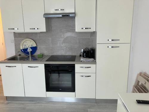 une cuisine avec des armoires blanches et un four noir dans l'établissement Appartement 2 pers hyper centre, à Le Touquet-Paris-Plage