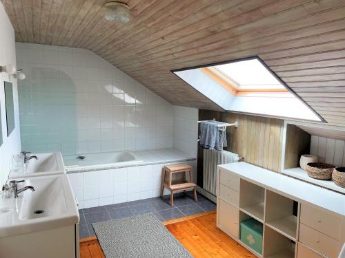 La salle de bains est pourvue d'une baignoire, d'un lavabo et d'une lucarne. dans l'établissement Grande maison familiale au cœur du Finistère, à Landudal