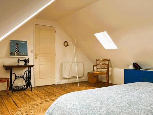 Cette chambre mansardée comprend un lit et une chaise. dans l'établissement Grande maison familiale au cœur du Finistère, à Landudal