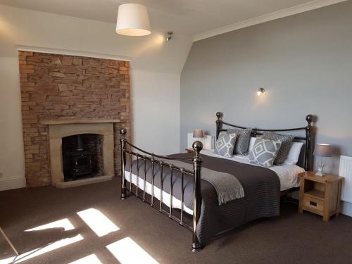 a bedroom with a bed and a brick fireplace at Beautiful Pendine Manor House in West Wales in Pendine
