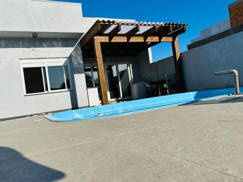 a swimming pool with a pergola in front of a building at Casa piscina MAJU in Imbé
