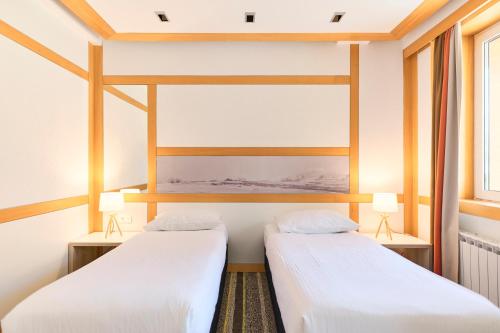 two beds in a room with two windows at Hotel Han Bjelašnica in Bjelašnica