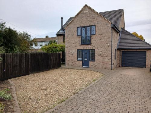 a brick house with a blue door and a fence at Woodlands Peaceful Bedrooms in Hemingford Grey