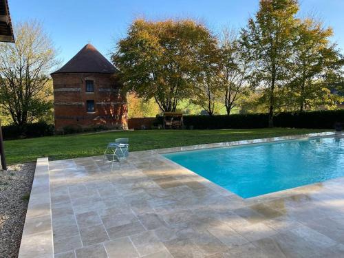 een zwembad voor een bakstenen gebouw bij Le Colombier d Yville in Héronchelles
