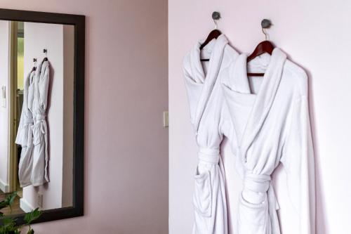 a white robe hanging on a wall next to a mirror at Royal Boutique Hotel in Cape Town