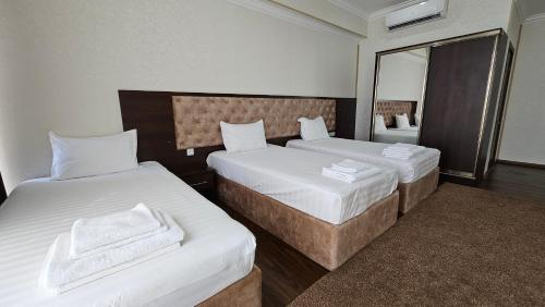 a hotel room with two beds and a mirror at Grand Turon Plaza Hotel in Tashkent