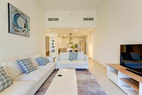 a living room with white couches and a tv at Serene 2-Bed Haven in Jumeirah Golf Estates in Dubai