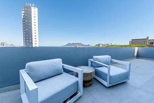 two chairs and a table on a balcony at Beachfront Apartment with wrap around terrace in Blouberg, 04 Azul in Bloubergstrand
