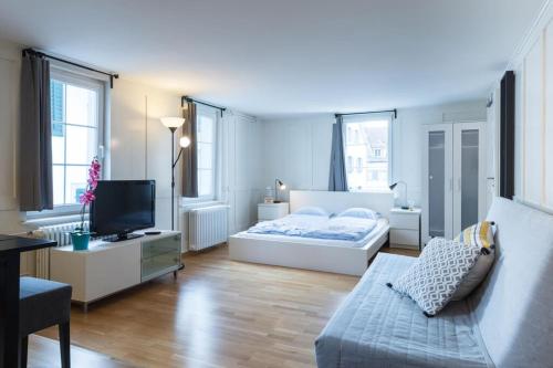 a white bedroom with a bed and a tv at HITrental Zeughausgasse - Apartment in Zug