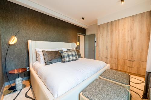 a bedroom with a white bed and a wooden wall at Beachfront Apartment with wrap around terrace in Blouberg, 04 Azul in Bloubergstrand