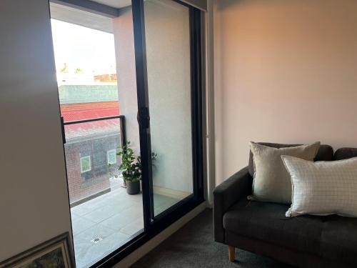 a living room with a couch and a sliding glass door at Modern apartment in Central Geelong! in Geelong