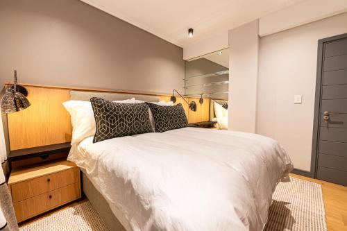 a bedroom with a large white bed with a wooden headboard at Beachfront Apartment with wrap around terrace in Blouberg, 04 Azul in Bloubergstrand