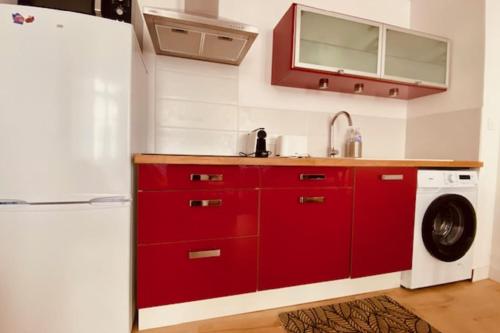 une cuisine avec des placards rouges et un lave-linge/sèche-linge dans l'établissement Apartment in La Rochelle close to amenities, à La Rochelle