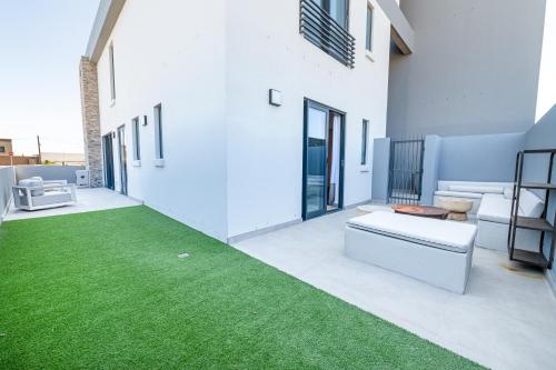 a patio with green grass on the side of a building at Beachfront Apartment with wrap around terrace in Blouberg, 04 Azul in Bloubergstrand