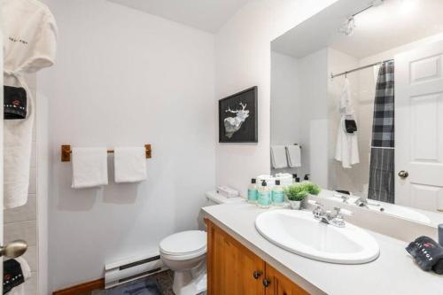 a white bathroom with a sink and a toilet at Hauts-bois Ski Inout 2brs Wpool Access 197-9 in Mont-Tremblant