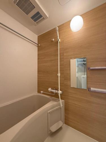 a bathroom with a bath tub and a mirror at Clio Matoba - Fully Equipped Studio Getaway in Hiroshima