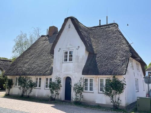 a white house with a black roof at Kapitänshaus von 1712 - neu saniert in Nieblum