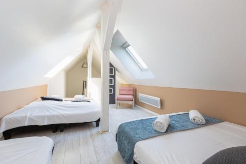 ein Schlafzimmer im Dachgeschoss mit zwei Betten und einem Sessel in der Unterkunft Villa 250m Spa privé, Borne d'arcade, Babyfoot - Gite des frères-Strasbourg in Hurtigheim