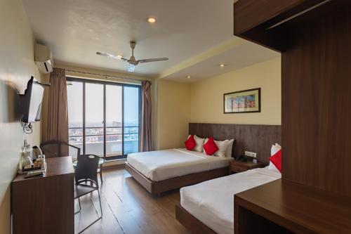 Una habitación de hotel con dos camas y una ventana. en Hotel Verandah, en Itahari