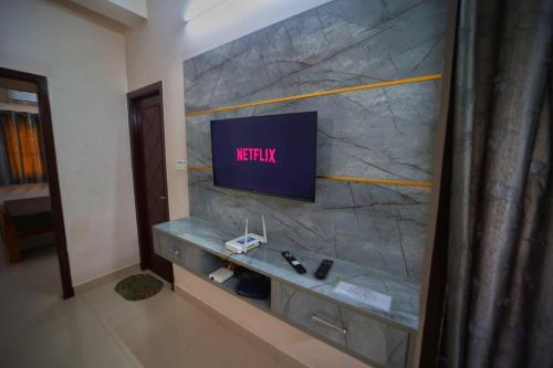 a living room with a tv on a stone wall at CM Stays Service Apartment - Near Chennai Airport - Pallavaram in Chennai