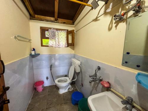 a bathroom with a toilet and a sink at Odyssey Stays Sathkol in Mukteswar