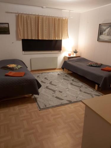a room with two beds and a television on the wall at Koivuharju in Kemi