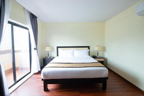 a bedroom with a bed and a large window at Mahasakor Inn in Phnom Penh