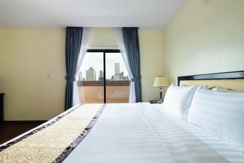 a bedroom with a large white bed with a window at Mahasakor Inn in Phnom Penh