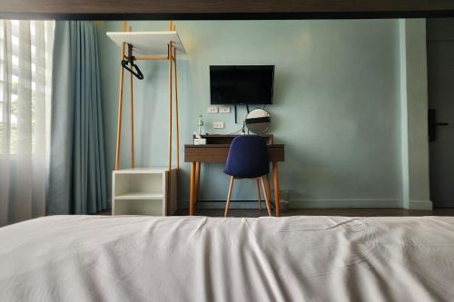 a bedroom with a bed and a desk with a television at Simply Sleep Hostel in Bangkok