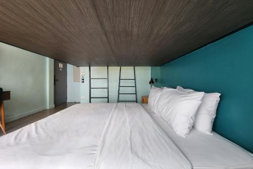 a large white bed with a blue wall at Simply Sleep Hostel in Bangkok