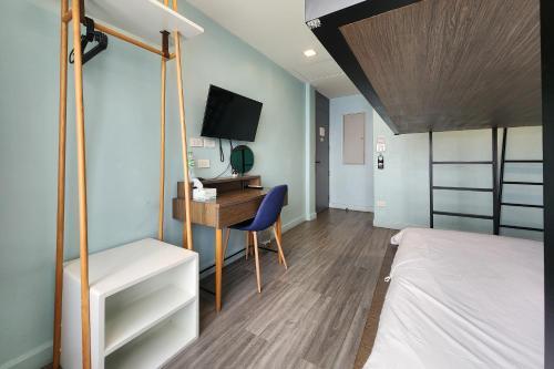 a bedroom with a bed and a desk with a television at Simply Sleep Hostel in Bangkok