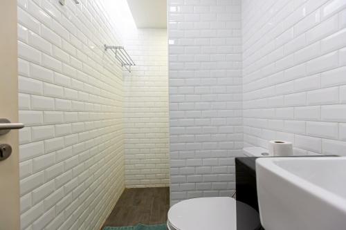 a white bathroom with a toilet and a sink at Simply Sleep Hostel in Bangkok