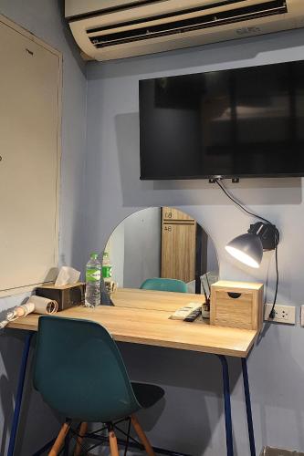 a desk with two chairs and a television on a wall at Simply Sleep Hostel in Bangkok